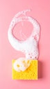 Yellow sponge with foam on pink background, top view. Royalty Free Stock Photo