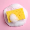 Yellow sponge with foam on pink background, top view. Royalty Free Stock Photo