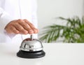 Man ringing hotel service bell at light table Royalty Free Stock Photo