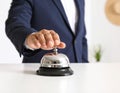 Man ringing hotel service bell at light table Royalty Free Stock Photo