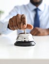 Man ringing hotel service bell at light table Royalty Free Stock Photo