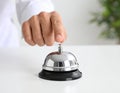 Man ringing hotel service bell at light table Royalty Free Stock Photo