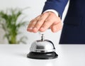 Man ringing hotel service bell at light table Royalty Free Stock Photo