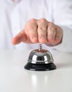 Man ringing hotel service bell at light table Royalty Free Stock Photo