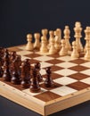 Many chess pieces on wooden checkerboard against black background, selective focus Royalty Free Stock Photo