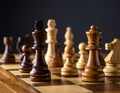 Many chess pieces on wooden checkerboard against black background, selective focus Royalty Free Stock Photo