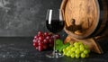Glass with delicious wine, wooden barrel and fresh grapes on black table Royalty Free Stock Photo