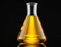 Glass flask with yellow oil on black background, closeup. Royalty Free Stock Photo