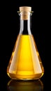 Glass flask with yellow oil on black background, closeup. Royalty Free Stock Photo