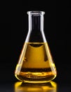 Glass flask with yellow oil on black background, closeup. Royalty Free Stock Photo