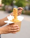 Woman eating takeaway noodles from paper box with fork outdoors, closeup. Street food Royalty Free Stock Photo