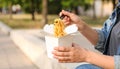 Woman eating takeaway noodles from paper box with fork outdoors, closeup. Street food Royalty Free Stock Photo