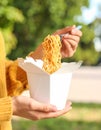 Woman eating takeaway noodles from paper box with fork outdoors, closeup. Street food Royalty Free Stock Photo