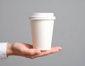 A woman holding a paper cup in front of a gray background. Creating a model Royalty Free Stock Photo