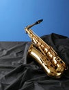 Jazz. A beautiful saxophone on dark fabric against a light blue background. Text area Royalty Free Stock Photo