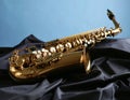 Jazz. A beautiful saxophone on dark fabric against a light blue background. Text area Royalty Free Stock Photo