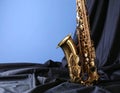 Jazz. A beautiful saxophone on dark fabric against a light blue background. Text area Royalty Free Stock Photo