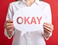 Woman holding paper speech bubble with word Okay on red background, closeup Royalty Free Stock Photo
