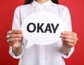 Woman holding paper speech bubble with word Okay on red background, closeup Royalty Free Stock Photo
