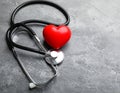 Stethoscope and red heart on grey stone table. Space for text Royalty Free Stock Photo
