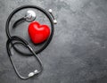 Stethoscope and red heart on grey stone table. Space for text Royalty Free Stock Photo