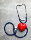Stethoscope and red heart on grey stone table. Space for text Royalty Free Stock Photo
