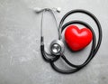 Stethoscope and red heart on grey stone table. Space for text Royalty Free Stock Photo