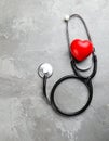 Stethoscope and red heart on grey stone table. Space for text Royalty Free Stock Photo