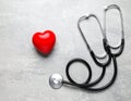 Stethoscope and red heart on grey stone table. Space for text Royalty Free Stock Photo