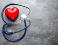 Stethoscope and red heart on grey stone table. Space for text Royalty Free Stock Photo