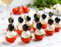 Tasty canapes with black olives, mozzarella and cherry tomatoes on white marble table Royalty Free Stock Photo