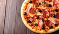 Tasty pizza with cured ham, olives, sun-dried tomato and pepper on wooden table Royalty Free Stock Photo