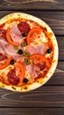Tasty pizza with cured ham, olives, sun-dried tomato and pepper on wooden table Royalty Free Stock Photo