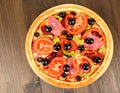 Tasty pizza with cured ham, olives, sun-dried tomato and pepper on wooden table Royalty Free Stock Photo