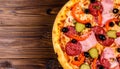 Tasty pizza with cured ham, olives, sun-dried tomato and pepper on wooden table Royalty Free Stock Photo