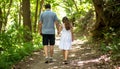 Couple walking hand-in-hand on forest trail with dappled sunlight Royalty Free Stock Photo