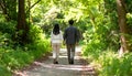 Couple walking hand-in-hand on forest trail with dappled sunlight Royalty Free Stock Photo