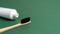 Close-up of bamboo toothbrush and toothpaste tube on minimalist matte dark green background Royalty Free Stock Photo