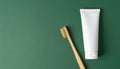 Close-up of bamboo toothbrush and toothpaste tube on minimalist matte dark green background Royalty Free Stock Photo