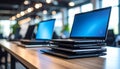 generated using AI.Laptops with blue screens are stacked on a wooden table in a modern office setting. Royalty Free Stock Photo