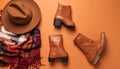 Flat Lay of Leather Ankle Boots, Wool Scarf, and Wide-Brimmed Felt Hat on Matte Burnt Orange Surface Royalty Free Stock Photo