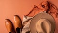 Flat Lay of Leather Ankle Boots, Wool Scarf, and Wide-Brimmed Felt Hat on Matte Burnt Orange Surface Royalty Free Stock Photo