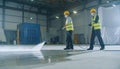 Industrial Workers in Safety Gear Power Washing a Factory Floor Royalty Free Stock Photo