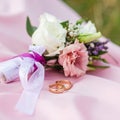 The wedding rings are tied with ribbons and beautiful flowers on pink fabric Royalty Free Stock Photo
