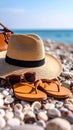 Beautiful hat with sunglasses, bag and flip flops near sea on pebble beach. Royalty Free Stock Photo