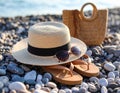 Beautiful hat with sunglasses, bag and flip flops near sea on pebble beach. Royalty Free Stock Photo