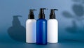 generated using AI.Three pump bottles are arranged on a blue surface with a soft blue background. Royalty Free Stock Photo