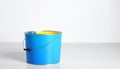 generated using AI.A metal paint can with a blue exterior stands on a light wooden floor against a white wall. Royalty Free Stock Photo
