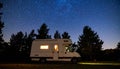 Camper van under starry sky glowing interior pine silhouettes Royalty Free Stock Photo
