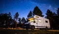 Camper van under starry sky glowing interior pine silhouettes Royalty Free Stock Photo